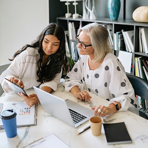 woman and young woman viewing tablet